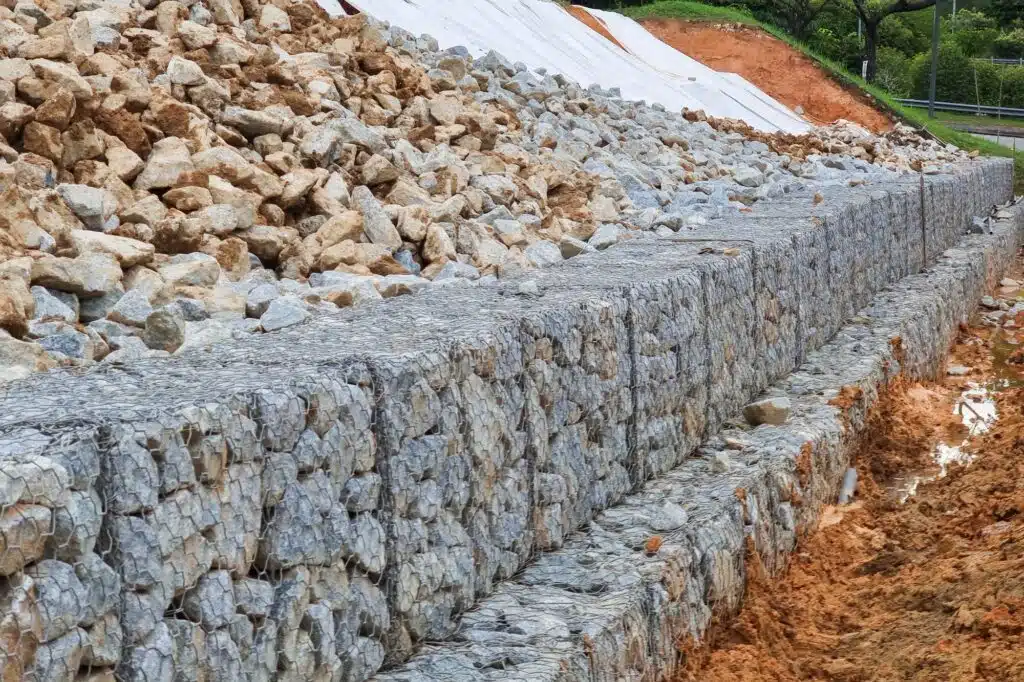 Series of close-up slope retention construction design with rocks and mesh to manage landslide
